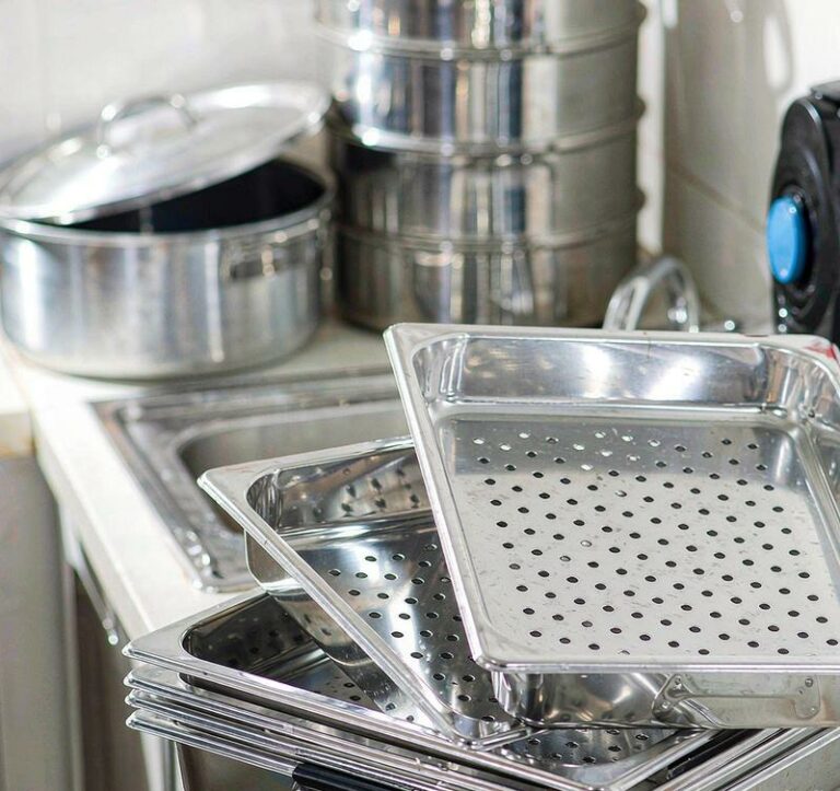 Aluminum baking trays and cookware stacked in commercial kitchen